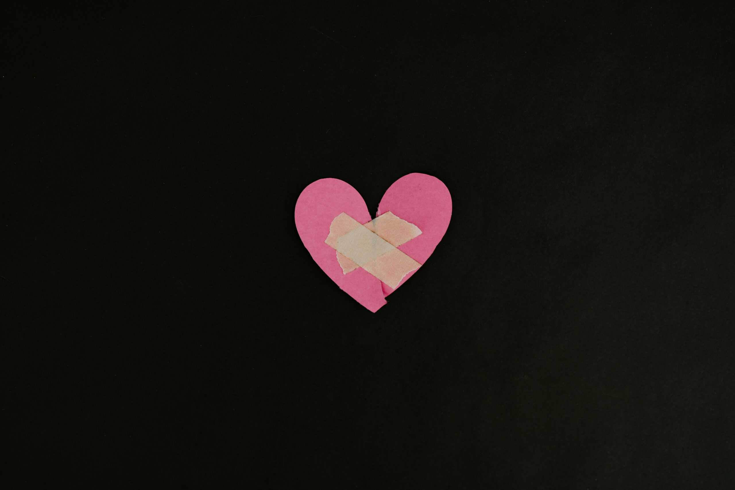 Two halves of a paper heart put together with tape.