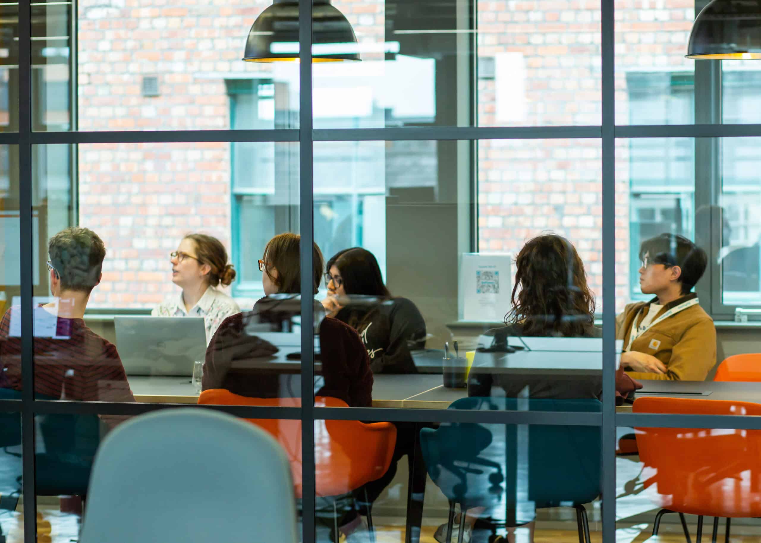 A group of Softwire employees sitting in discussion around a table in a meeting room.