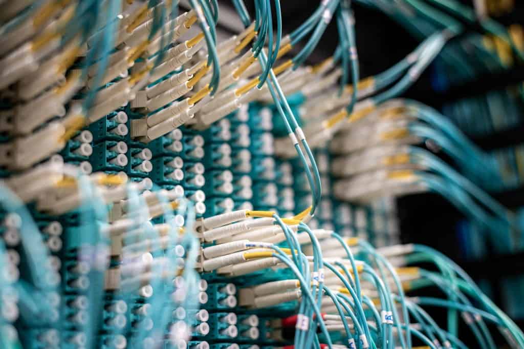 Detailed image of blue fiber optic cables in a data center with equipment connections.