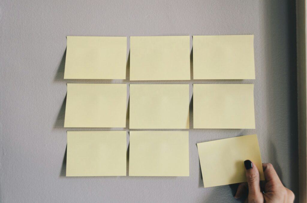 Nine post it notes on a wall with a hand removing one.