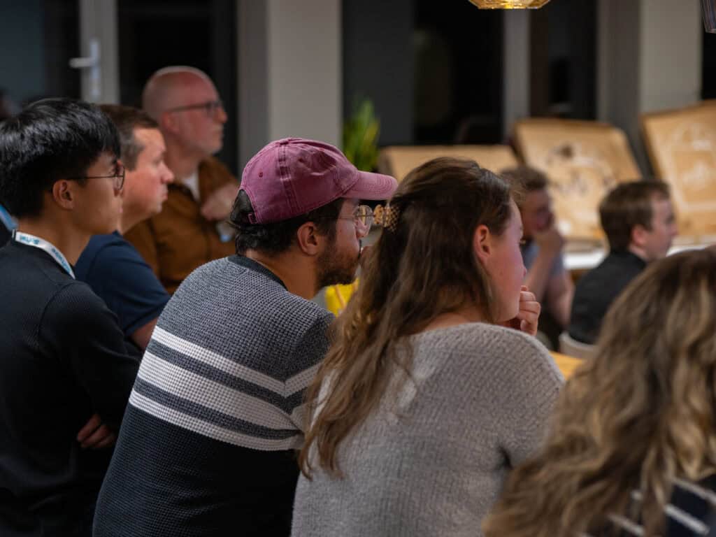 A backwards shot of attendees at an event listening to a speaker.